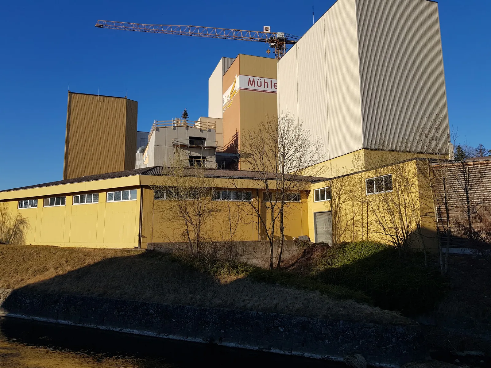 Gelbe Mühlengebäude mit Siloturm unter blauem Himmel