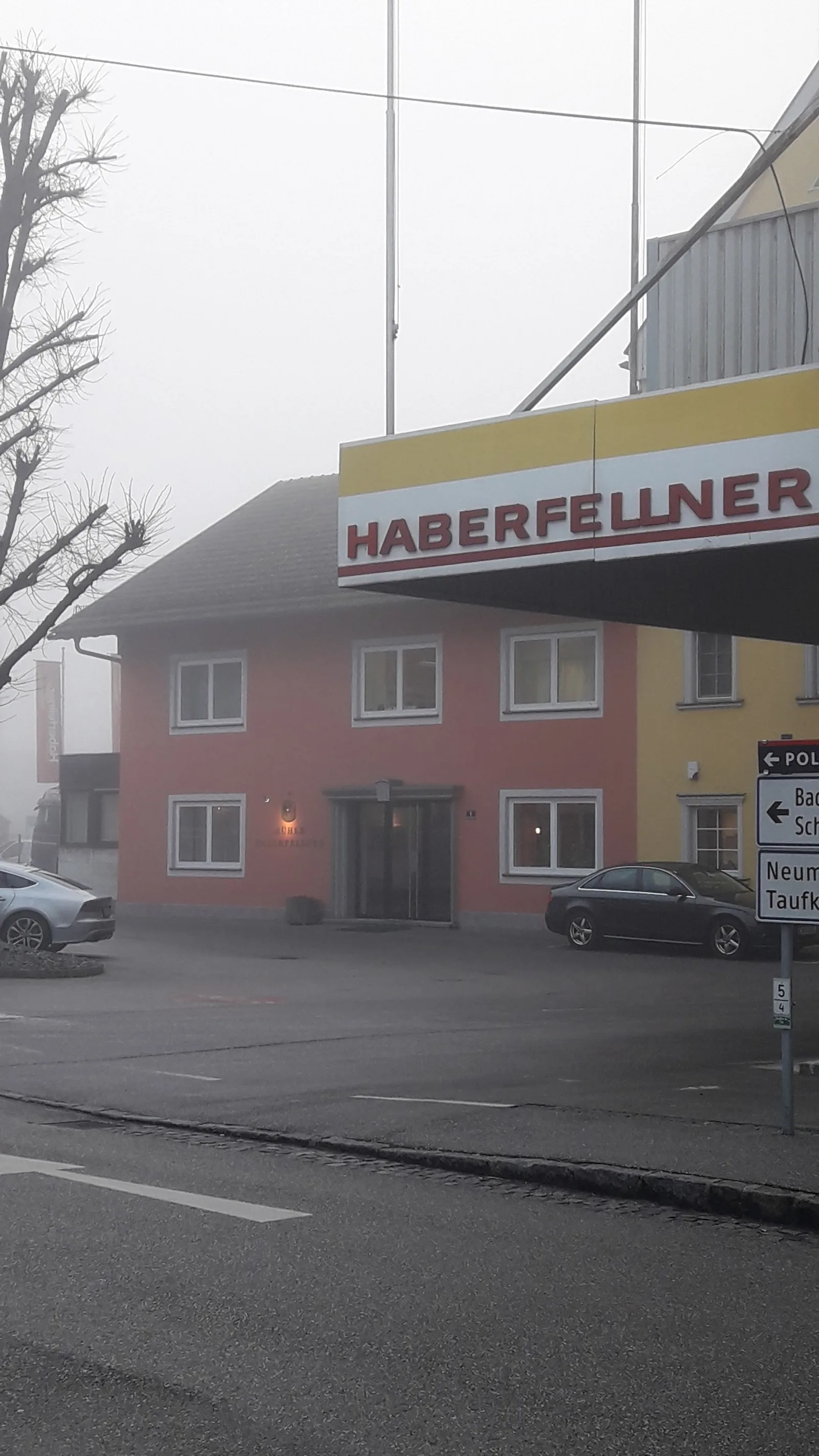 Gebäude mit Haberfellner-Schild über der Einfahrt im Nebel