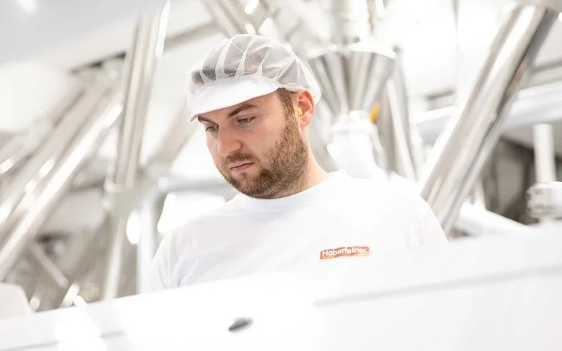 Mitarbeiter mit Haarnetz und Haberfellner-Shirt an einer Anlage der Mühle